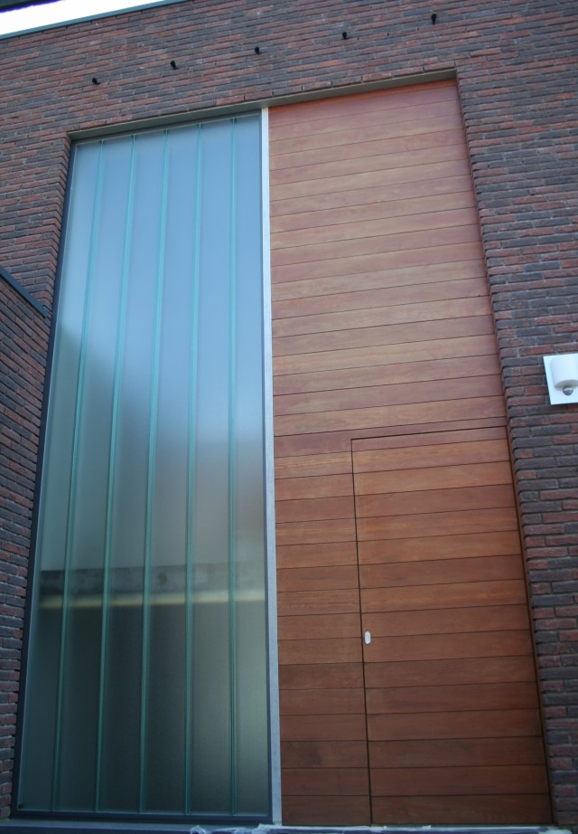 Massief houten voordeur in horizontale planchetten ingewerkt in de gevelbekleding